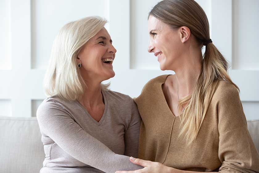 Happy older mother and adult daughter hugging, having fun together